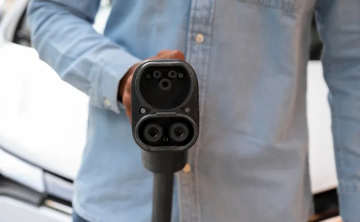 Personne tenant une prise de recharge électrique